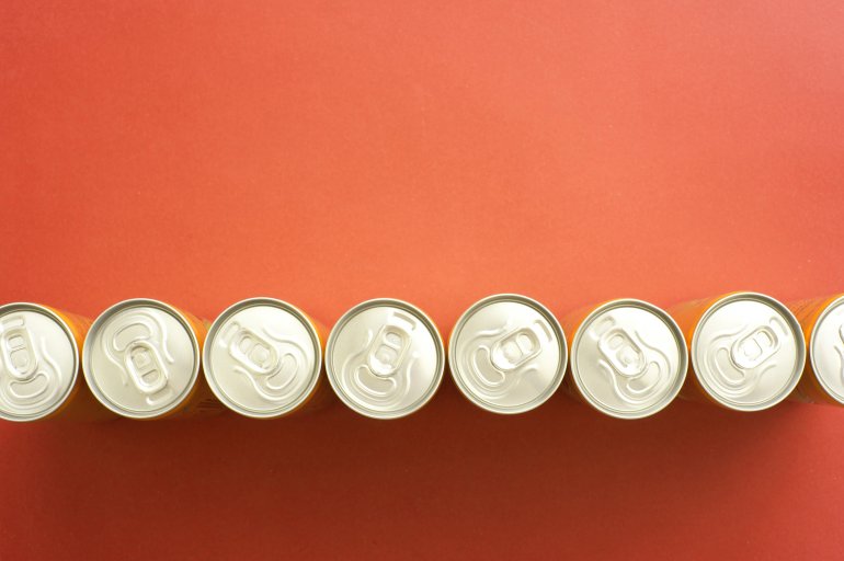 High Angle View of Soda Cans in a Row High Angle Still Life of Tops of Soda or Beer Cans Arranged in Line Across Orange Background with Copy Space - Generic Abstract Background