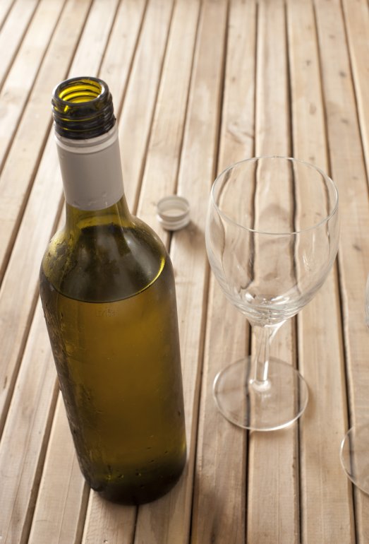 Bottle of white wine left standing to breath Opened unlabelled bottle of white wine left standing to breath standing on a wooden table with two empty wine glasses, with copyspace