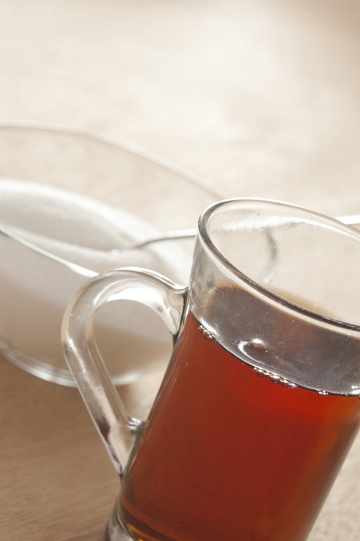 Glass cup of black tea with sugar Close up angled view of a glass cup of black tea with sugar in a sugar bowl behind for a refreshing beverage