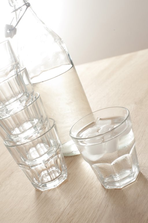 Glass of ice cold water Glass of ice cold water in a tumbler with a reusable glass bottle from the refrigerator full of healthy pure water with additional empty glasses alongside