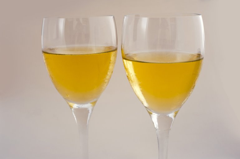 Two glasses of white wine Close up of two full glasses of white wine standing side by side over a grey background conceptual of viticulture, entertaining and relaxation