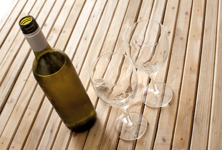 Bottle of opened white wine with two empty wine glasses viewed high angle on a wooden table conceptual of a celebration or entertaining