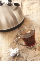 Mug of Tea Brewing on Table Beside Kettle