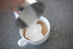 Adding steamed frothy milk to cappuccino