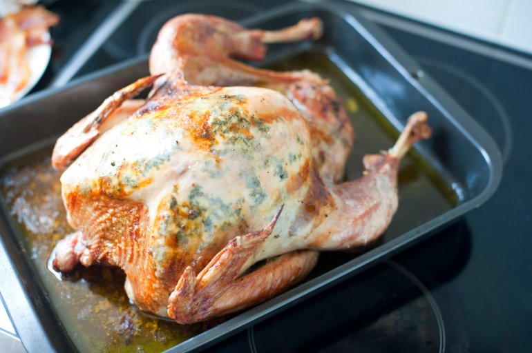 High angle view of a tasty golden whole roasted festive turkey in an oven pan during the preparation of a Thanksgiving or Christmas meal