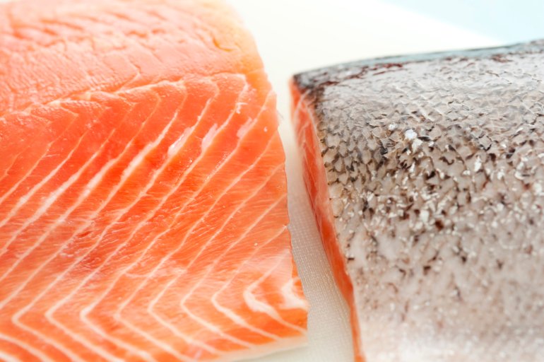Close up overhead view of two fresh salmon fillets one displaying the flesh and the other the texture of the cleaned silver skin
