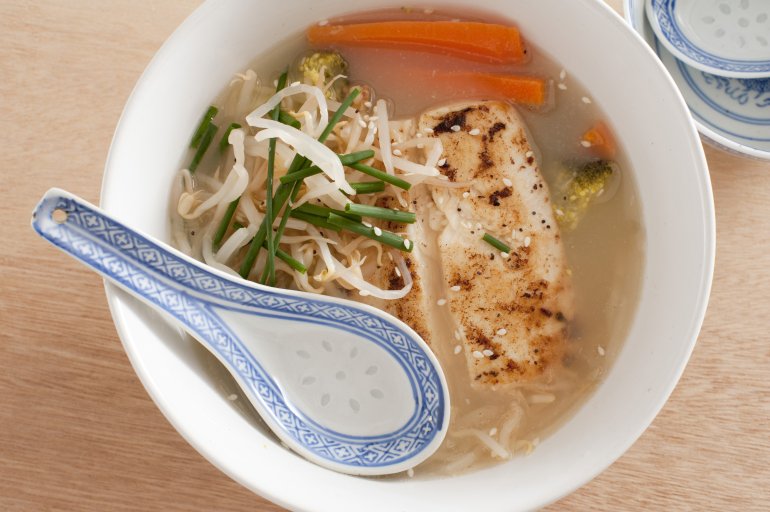 Above view on ornate spoon in bowl of Thai fish with chives, bean sprouts and carrot slices