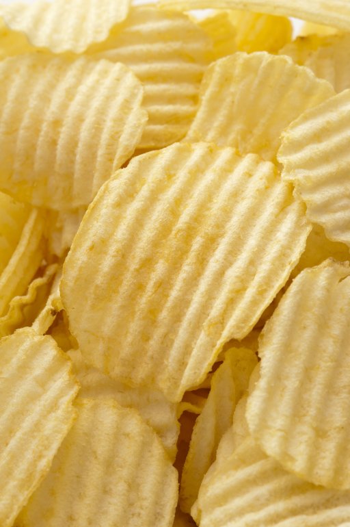 Close up on full frame view of ridged yellow potato chips with copy space for background about food and snacking