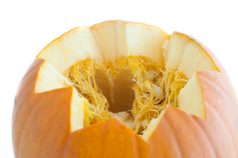 Pumpkin cut open at the top in a fancy zig zag pattern to reveal the fibres and pips inside