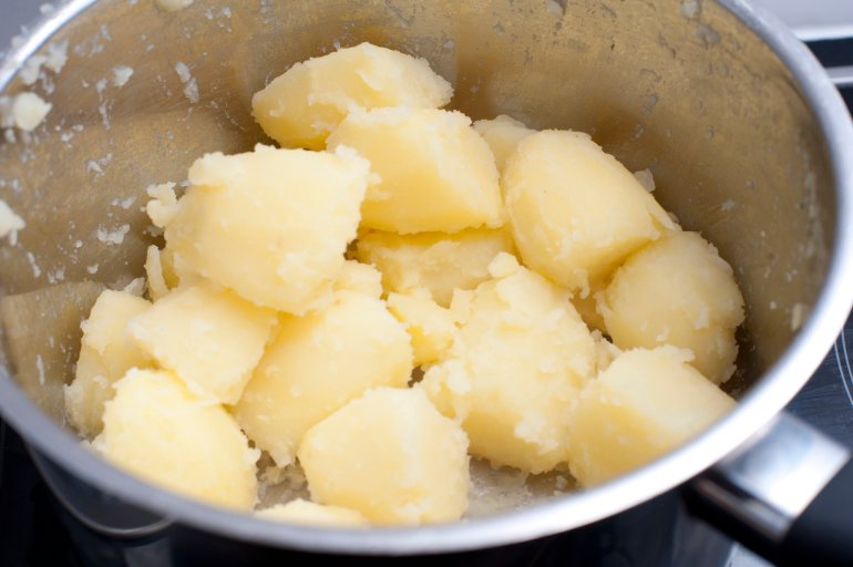 High angle view of parboiled diced potatoes in a steel pot being prepared for oven roasting