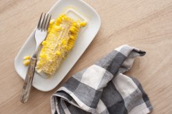 Eaten corn cob on white plate with fork
